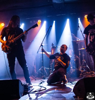 Band performing live on stage with dramatic lighting and intense expressions.