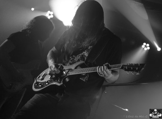 Musician playing electric guitar on stage, with dramatic lighting effects.