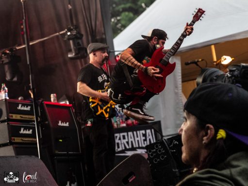 Two guitarists performing energetically on stage, with one jumping in mid-air.