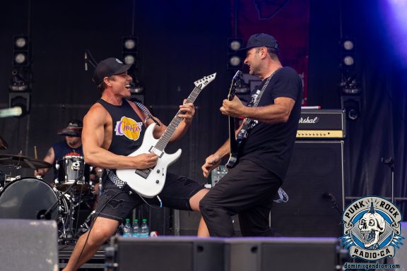 Two musicians perform on stage with electric guitars, engaging in a lively performance.