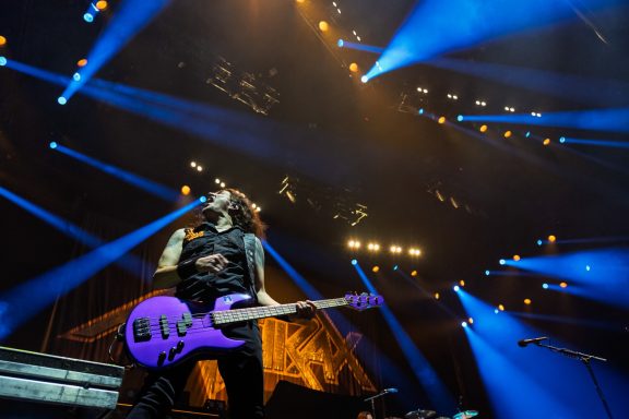 Anthrax - Centre Videotron Musician performs on stage with a purple guitar amidst vibrant blue lights.