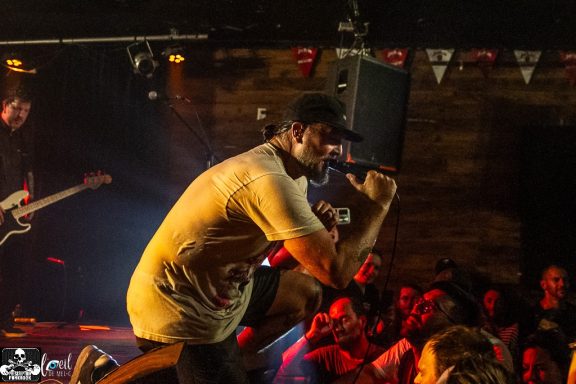 A musician performing energetically on stage, engaging with an enthusiastic crowd.