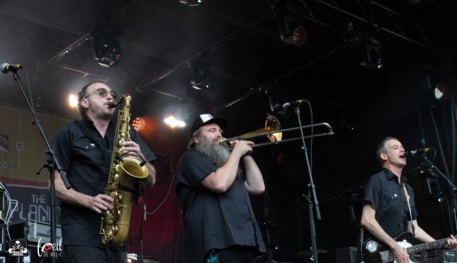 Musicians performing on stage with a saxophone, trombone, and vocals.