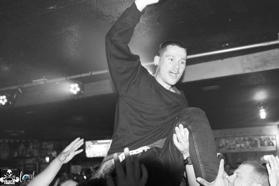 A crowd surfers during a lively performance in a dark venue.