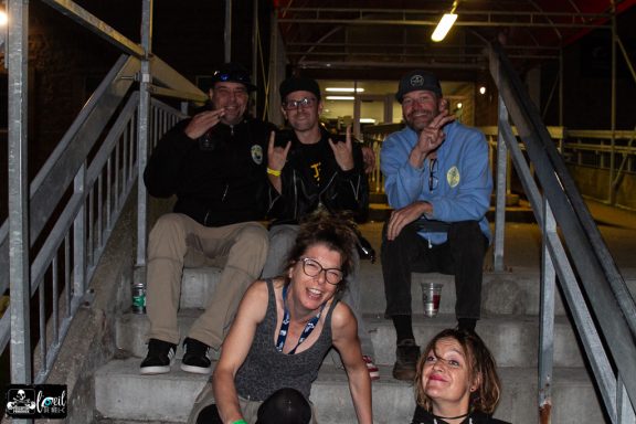 Group of five people posing and sitting on outdoor stairs at night.