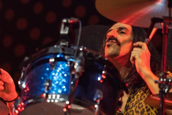 The Damn Truth - Centre Videotron Drummer performs energetically, surrounded by vibrant stage lights and colorful drum set.