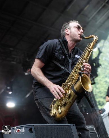 Saxophonist performing on stage with sunglasses, immersed in the music.