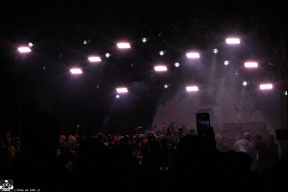 Crowd at a concert under bright stage lights with a dark backdrop.