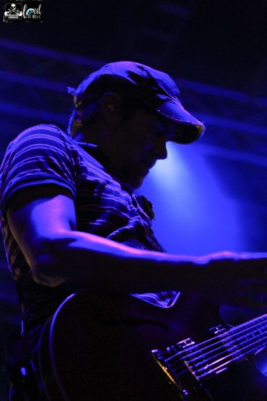 Silhouette of a person playing guitar under blue stage lights.