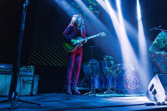 The Damn Truth - Centre Videotron A musician in a vibrant suit performs with an electric guitar on stage.