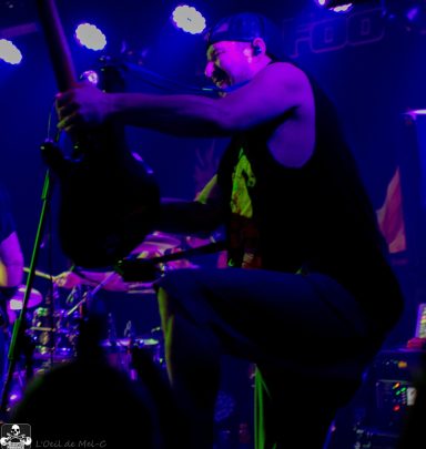 Musician playing guitar on stage with vibrant lighting and energetic atmosphere.