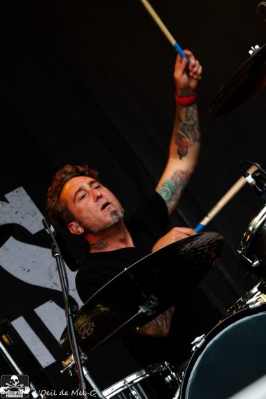 Drummer performing passionately on stage, focused on playing the drums.