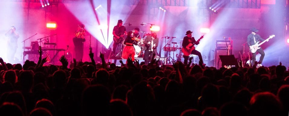 A lively concert scene with a band performing under colorful stage lights, crowd cheering.