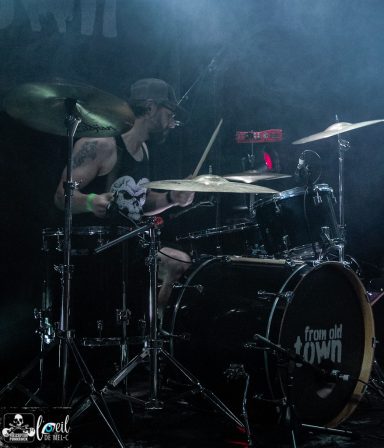 From Old Town - L'Anti-Bar & Spectacles Drummer playing passionately on stage surrounded by smoke and dynamic lighting.