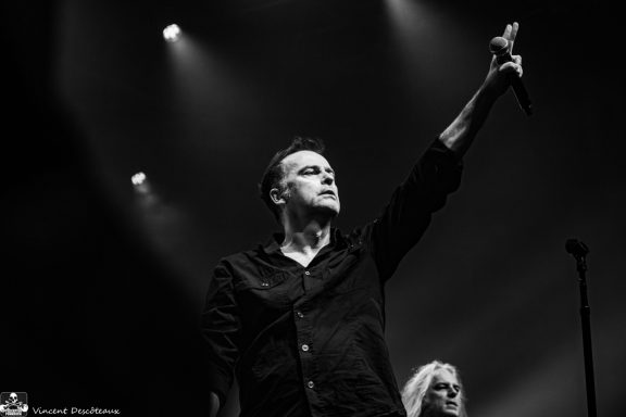 A singer performing passionately on stage with dramatic lighting.