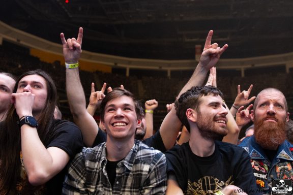A crowd of fans enjoying a concert, showing excitement and enthusiasm with raised hands.
