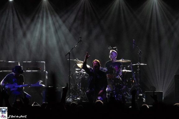 Band performing on stage with dramatic lighting and an engaged audience.