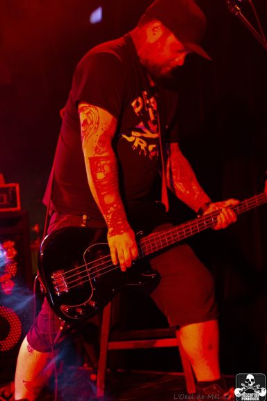 A musician playing bass guitar on stage with dramatic lighting effects.