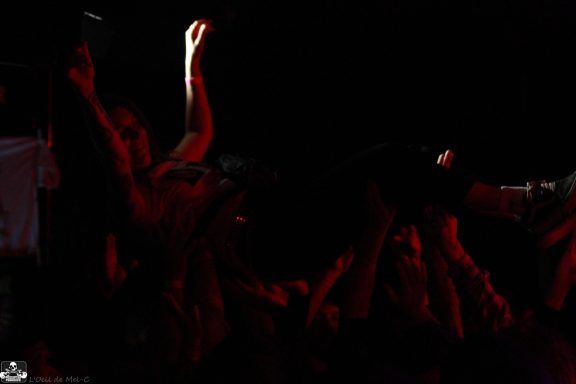 A crowd surfing against a dark background with red lighting.