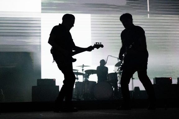 Silhouettes of musicians performing on stage with dynamic lighting.