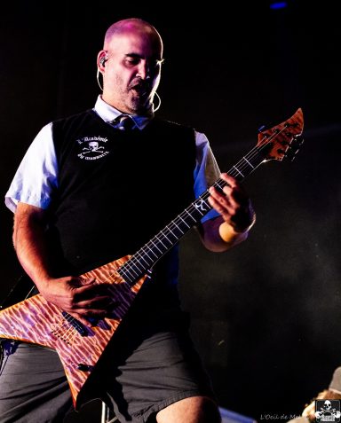 Man in a black vest playing an electric guitar on stage.