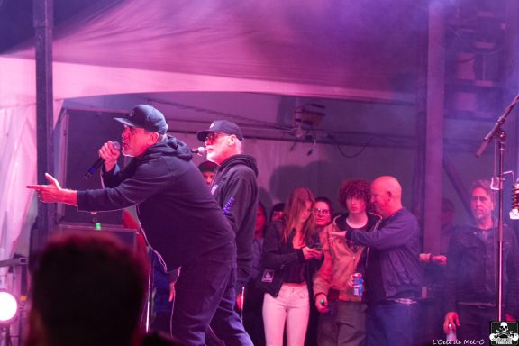 Two performers rap on stage with a crowd enjoying the energetic atmosphere.