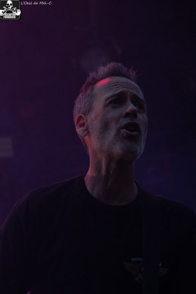 A musician singing passionately on stage with a dramatic purple light.