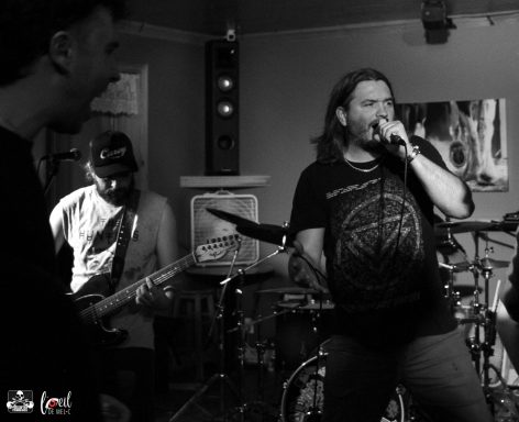 Band performing live on stage, vocalists and guitarist engaged with enthusiastic audience.