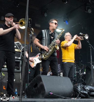 Musicians performing with brass instruments and a saxophone on stage.