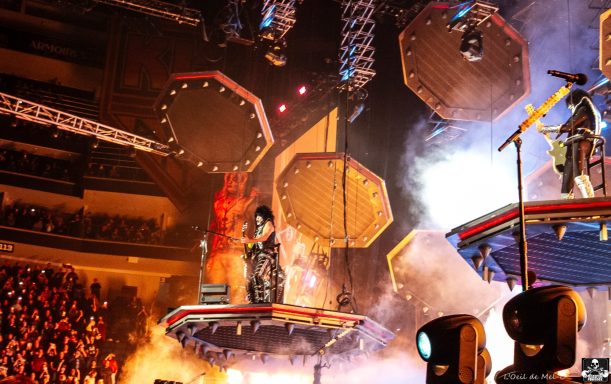 A performer in a dynamic stage setup with vibrant lights and smoke effects.