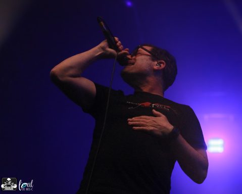 Singer performing on stage with a microphone, illuminated by stage lights.