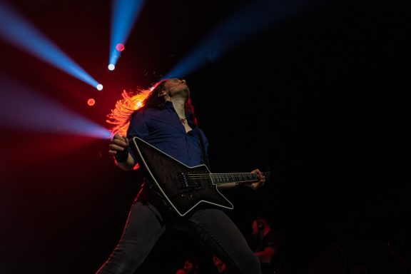 Megadeth - Centre Videotron A guitarist passionately playing on stage with dramatic lighting.