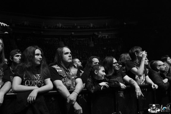 A crowd of concertgoers in black attire, eagerly watching the performance.