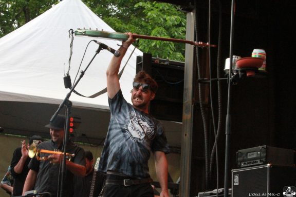 Musician playing a guitar enthusiastically at an outdoor performance.