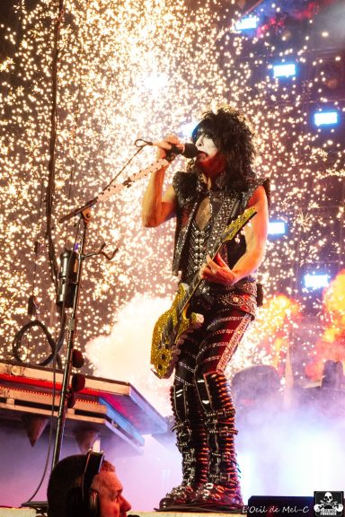 Rock musician performing on stage with a guitar, surrounded by fireworks and vibrant lights.