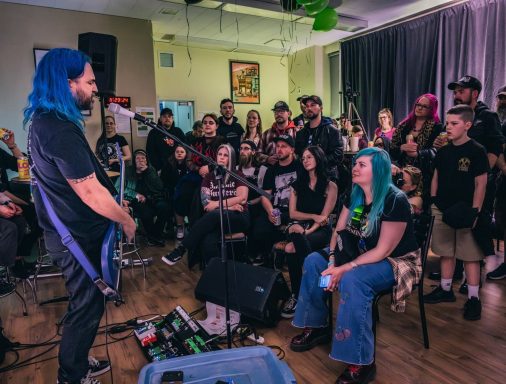 Rouge Pompier - Radiothon CKRL 89,1 A musician with blue hair performs to an engaged audience in a casual setting.