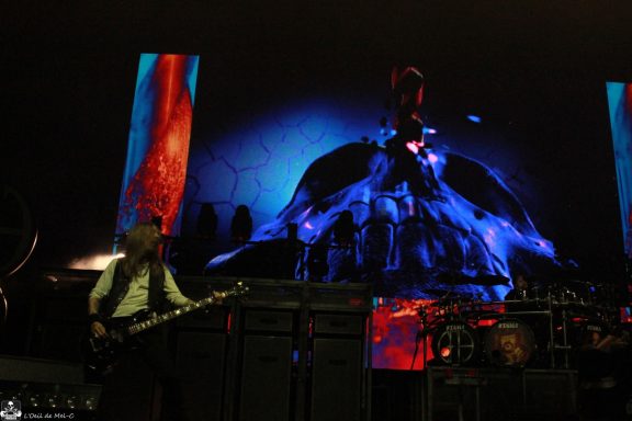 Musician performing on stage with vibrant visual projections in the background.