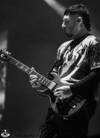 Musician playing electric guitar on stage in black and white.