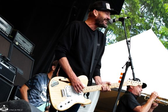 A musician plays guitar and sings on stage with a band during a performance.