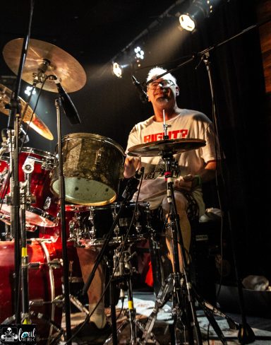 Dead Bob - La Source de la Martinière Drummer performing on stage with a drum kit and vibrant lights in the background.