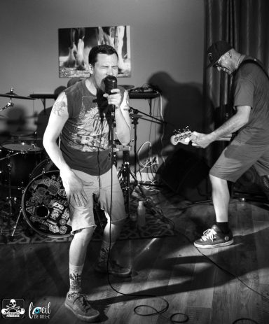 Band performing on stage, with a vocalist singing and a guitarist playing.