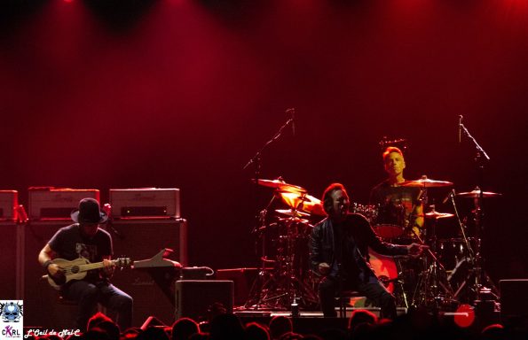 Band performing on stage with dramatic red lighting and energetic movement.