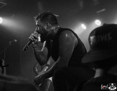 A singer performs passionately on stage under dramatic lighting.