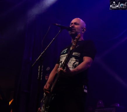 Millencolin - Red Bridge Fest 2026 A musician performing on stage with a microphone and guitar in a dimly lit setting.