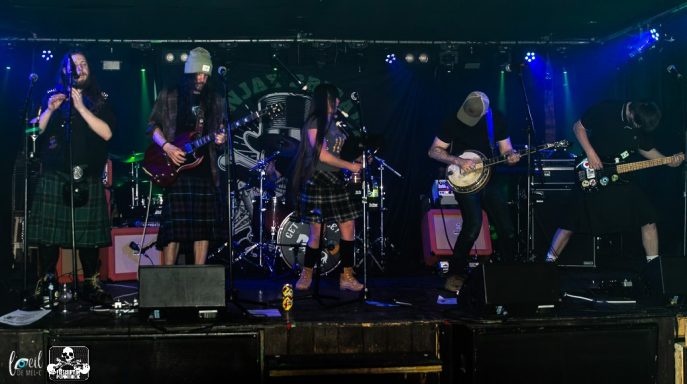 A band performing on stage with instruments and vibrant lighting.