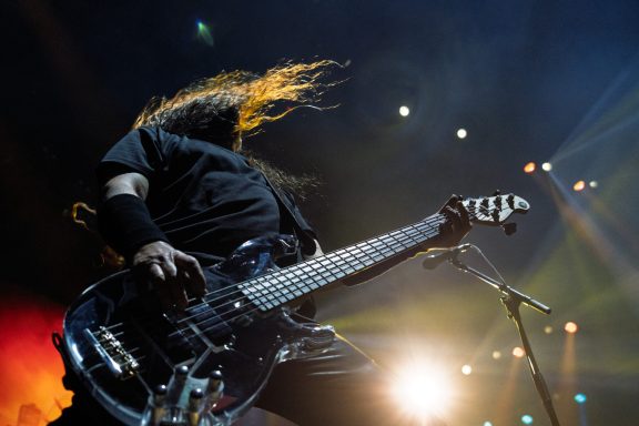 A musician playing an electric guitar with dynamic lighting and flowing hair.