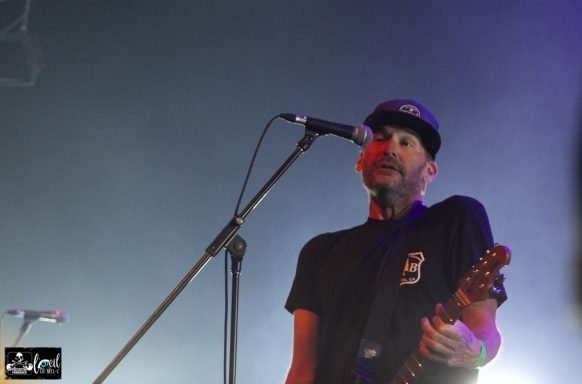 Musician performing live on stage with a guitar and microphone.