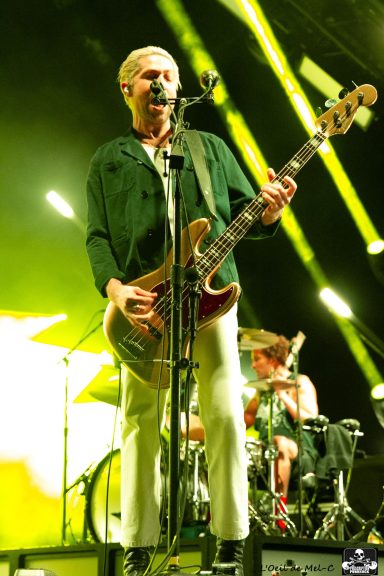 A musician passionately performing on stage with a guitar and vibrant lighting.