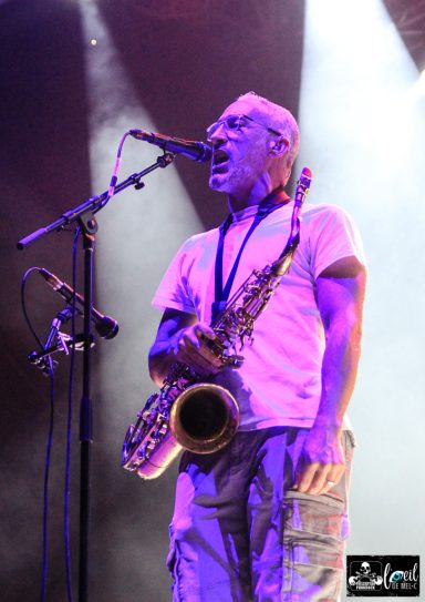 A musician passionately playing the saxophone on stage under dramatic lighting.