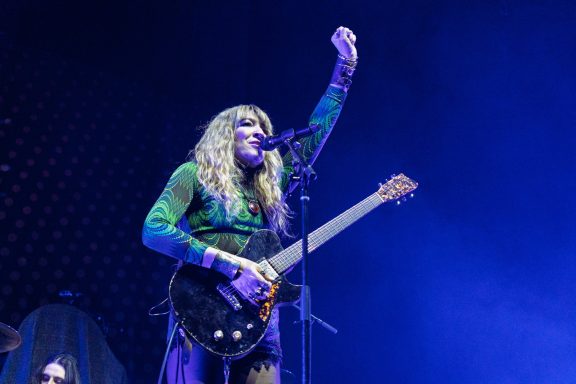 The Damn Truth - Centre Videotron A musician with long hair performs on stage, holding a guitar and raising a hand.